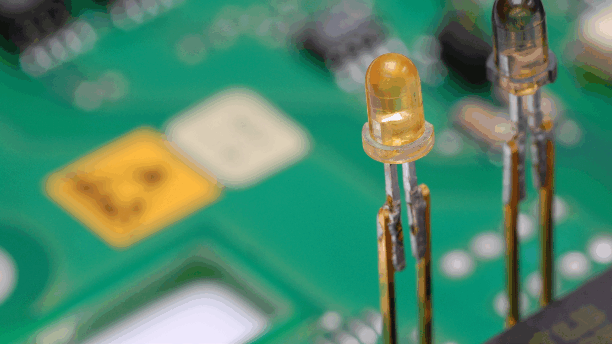 Gros plan sur une carte de circuit imprimé avec des composants électroniques, montrant deux diodes lumineuses (LED) déjà soudées en place.