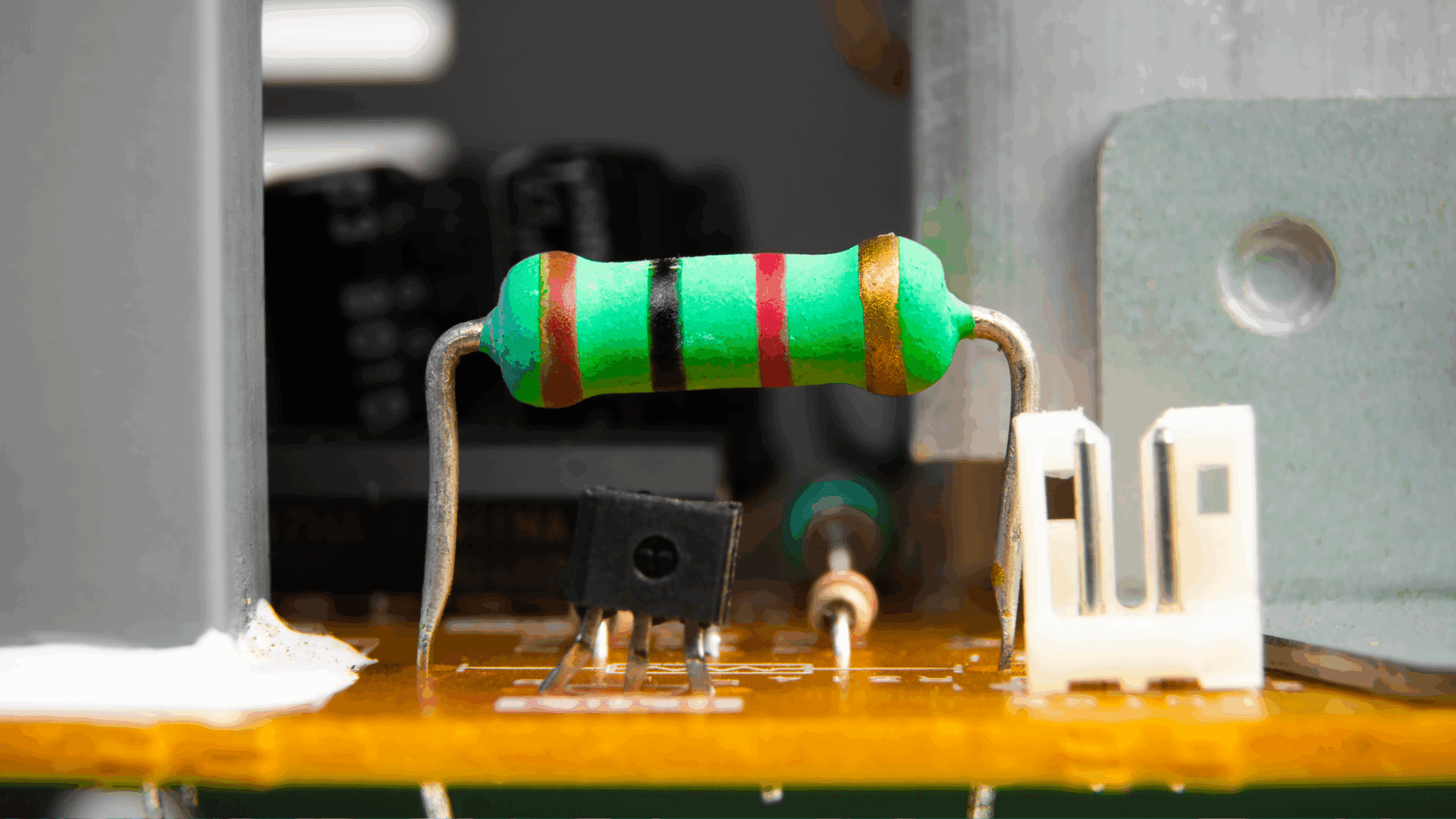 Gros plan sur des résistances à trou traversant avec des bandes de couleur, montées sur un PCB pour un circuit électronique.