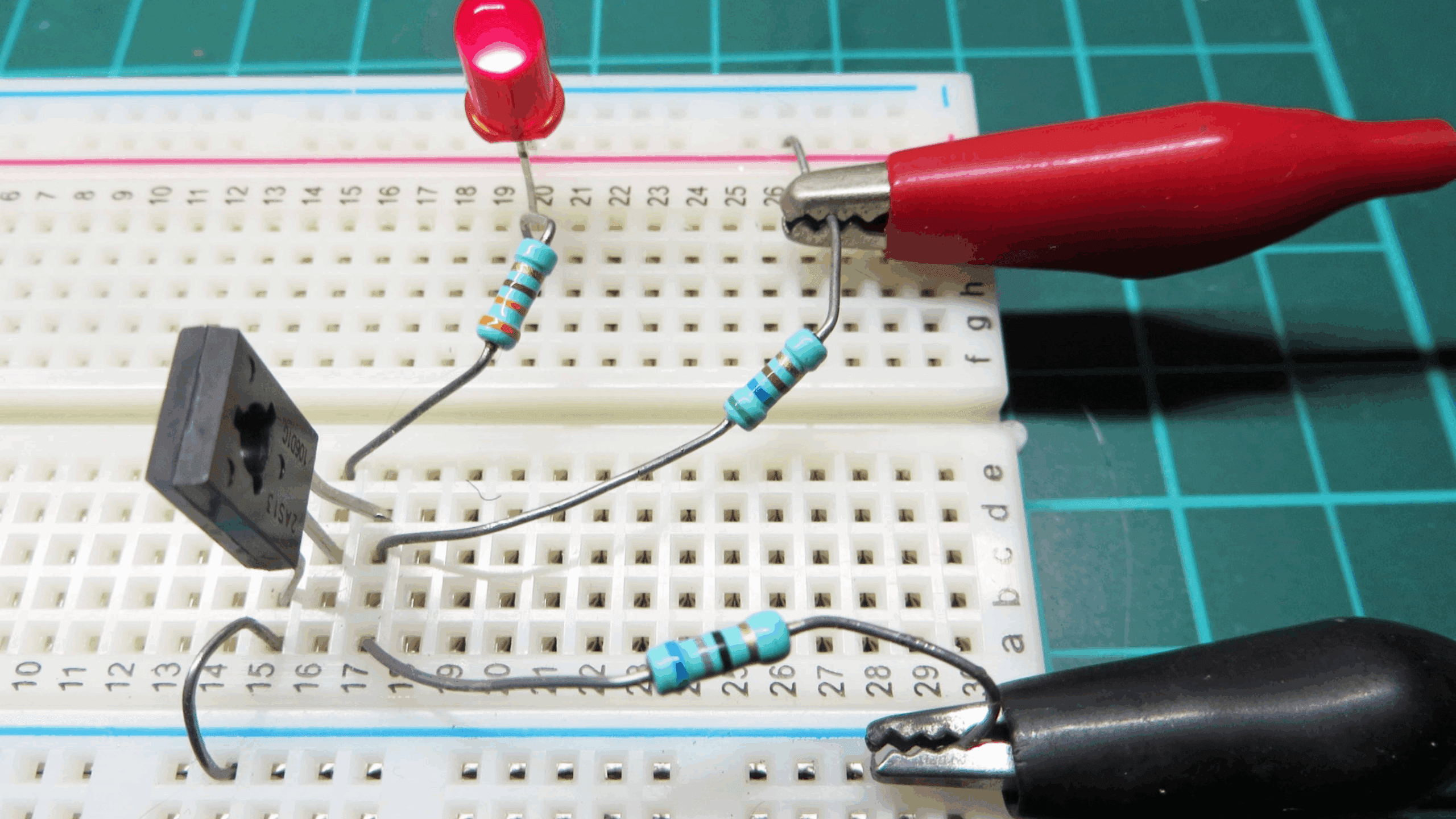 Circuit de test d'un thyristor sur une plaque d'essai avec une LED rouge et des sondes de mesure.
