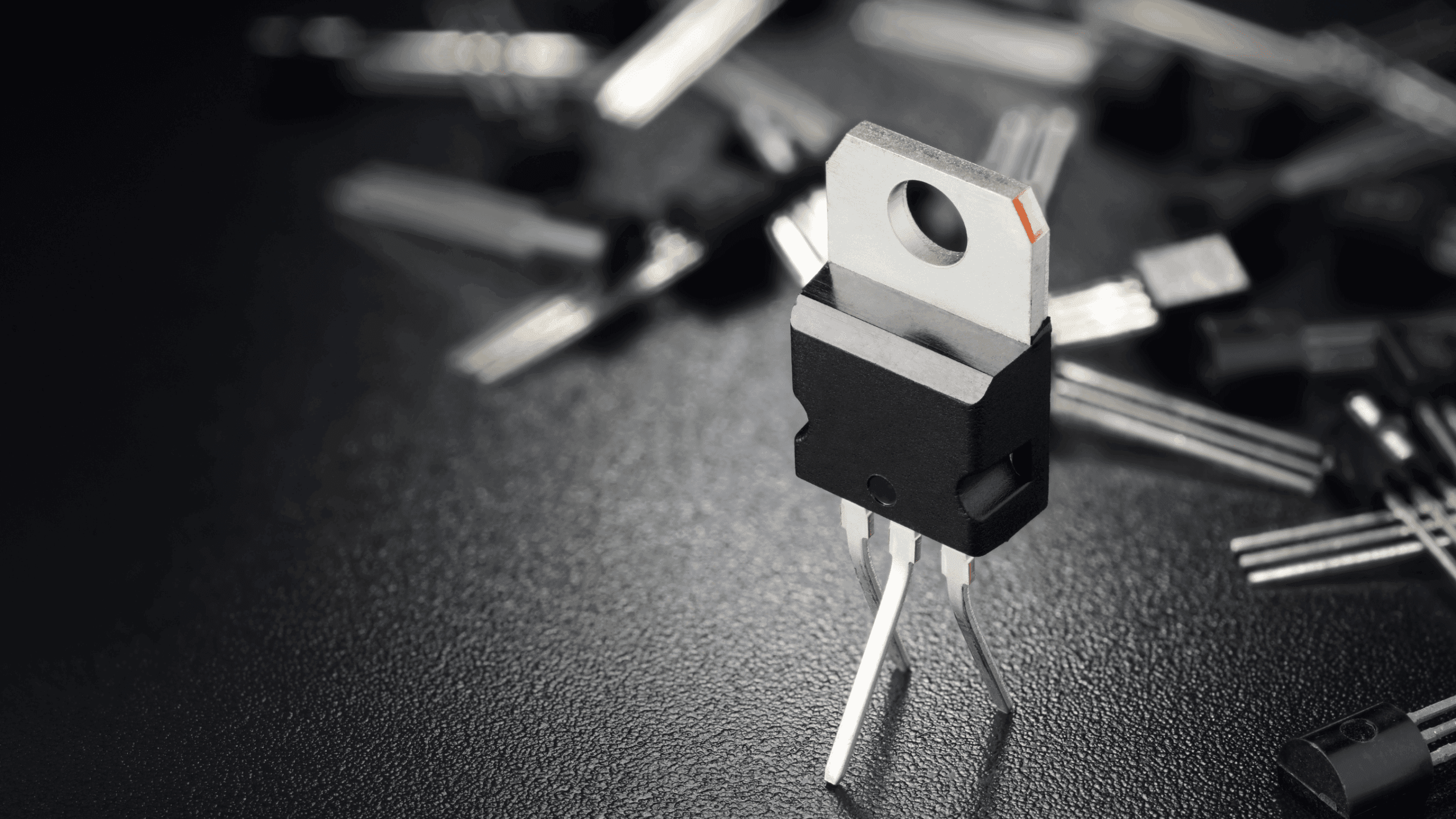 Gros plan d'un transistor MOSFET de puissance TO-220 sur un fond noir.