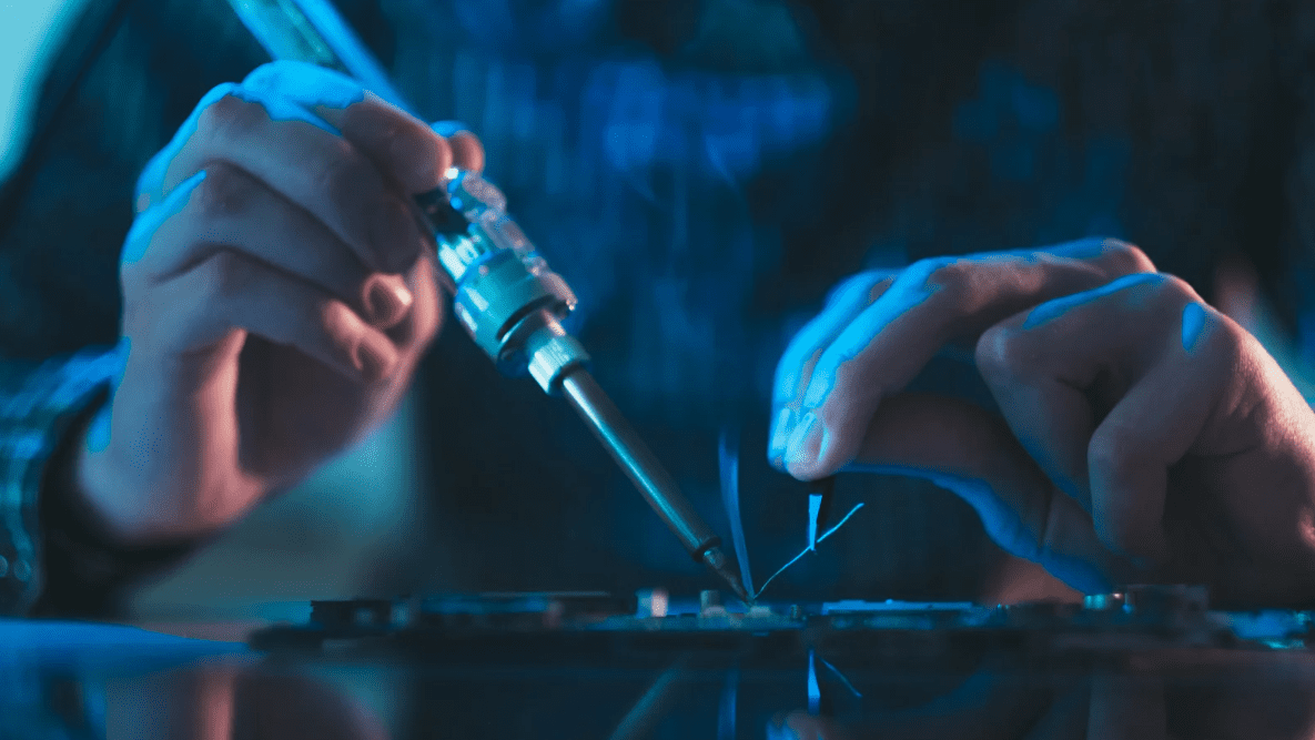 Personne réalisant une soudure électronique pour débutant sur un circuit imprimé avec un fer à souder.